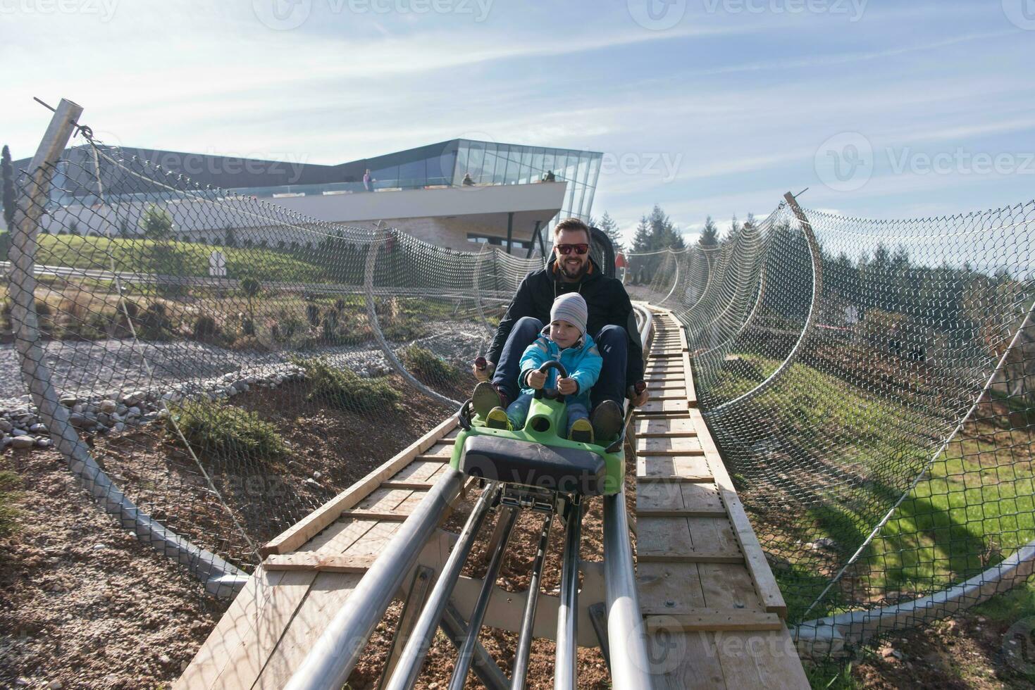 father and son enjoys driving on alpine coaster photo