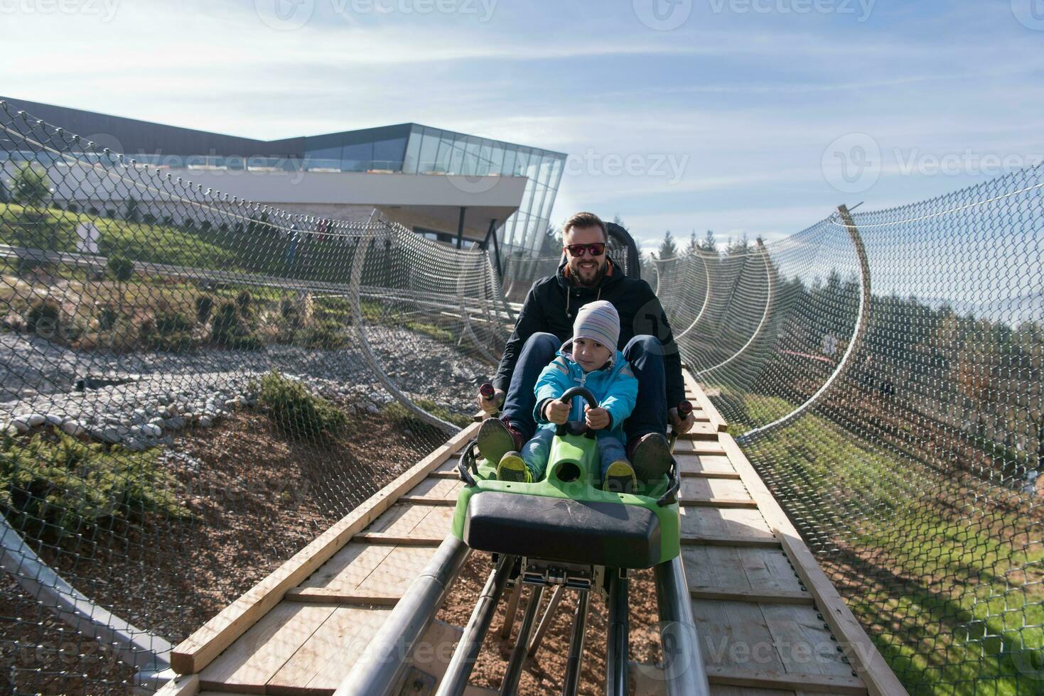 father and son enjoys driving on alpine coaster photo