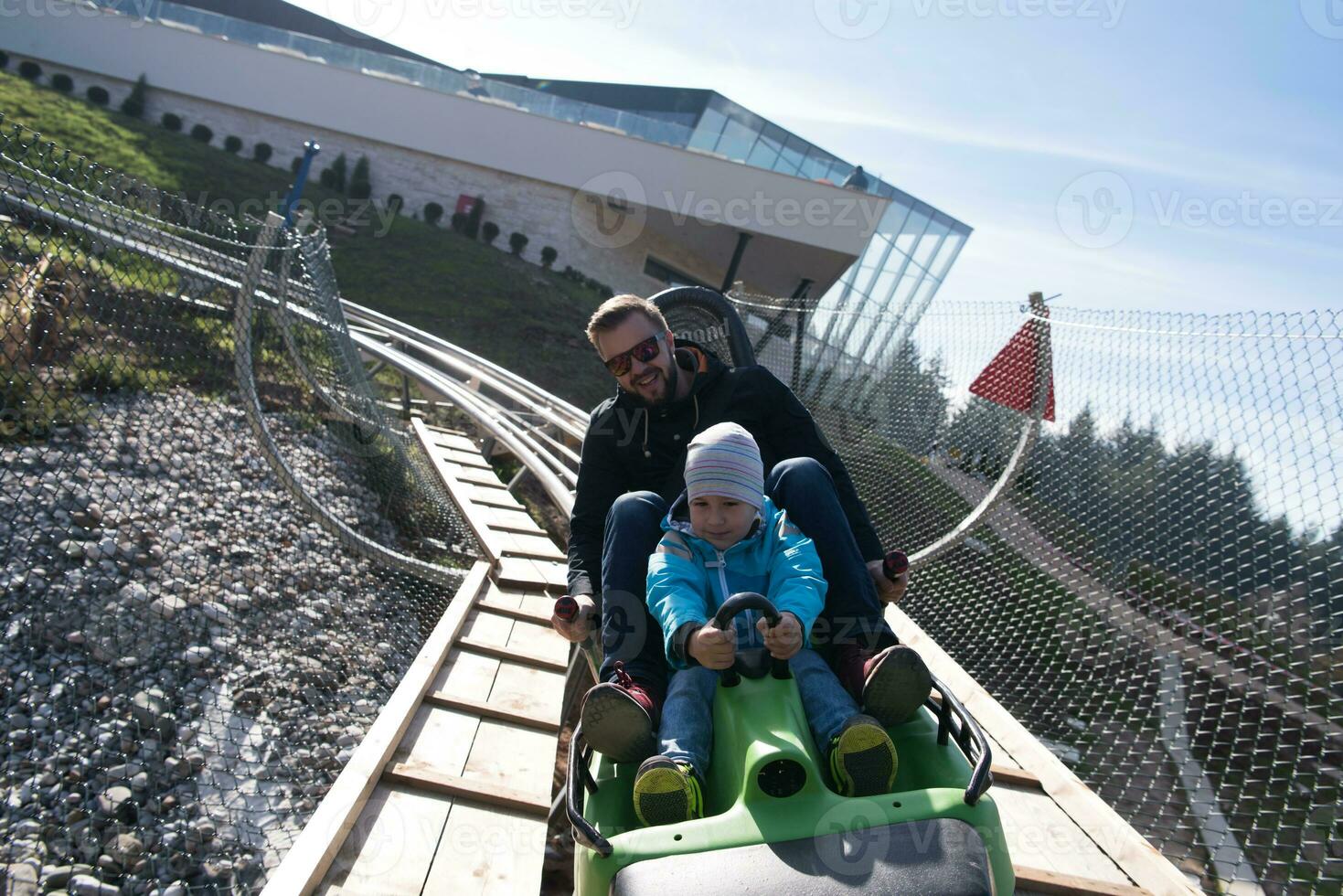 father and son enjoys driving on alpine coaster photo