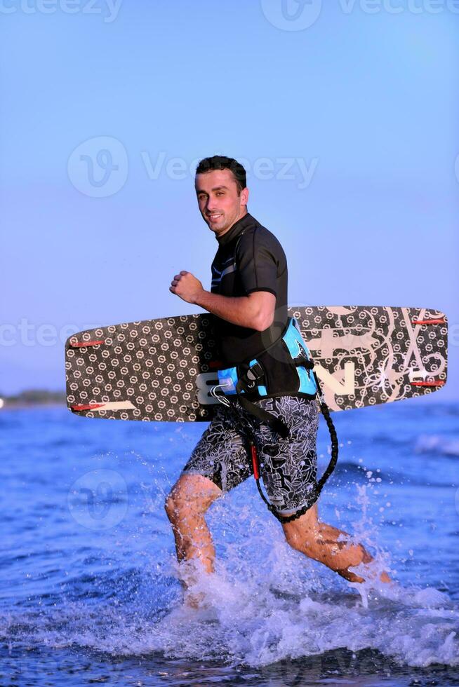 Portrait of a young  kitsurf  man at beach on sunset photo