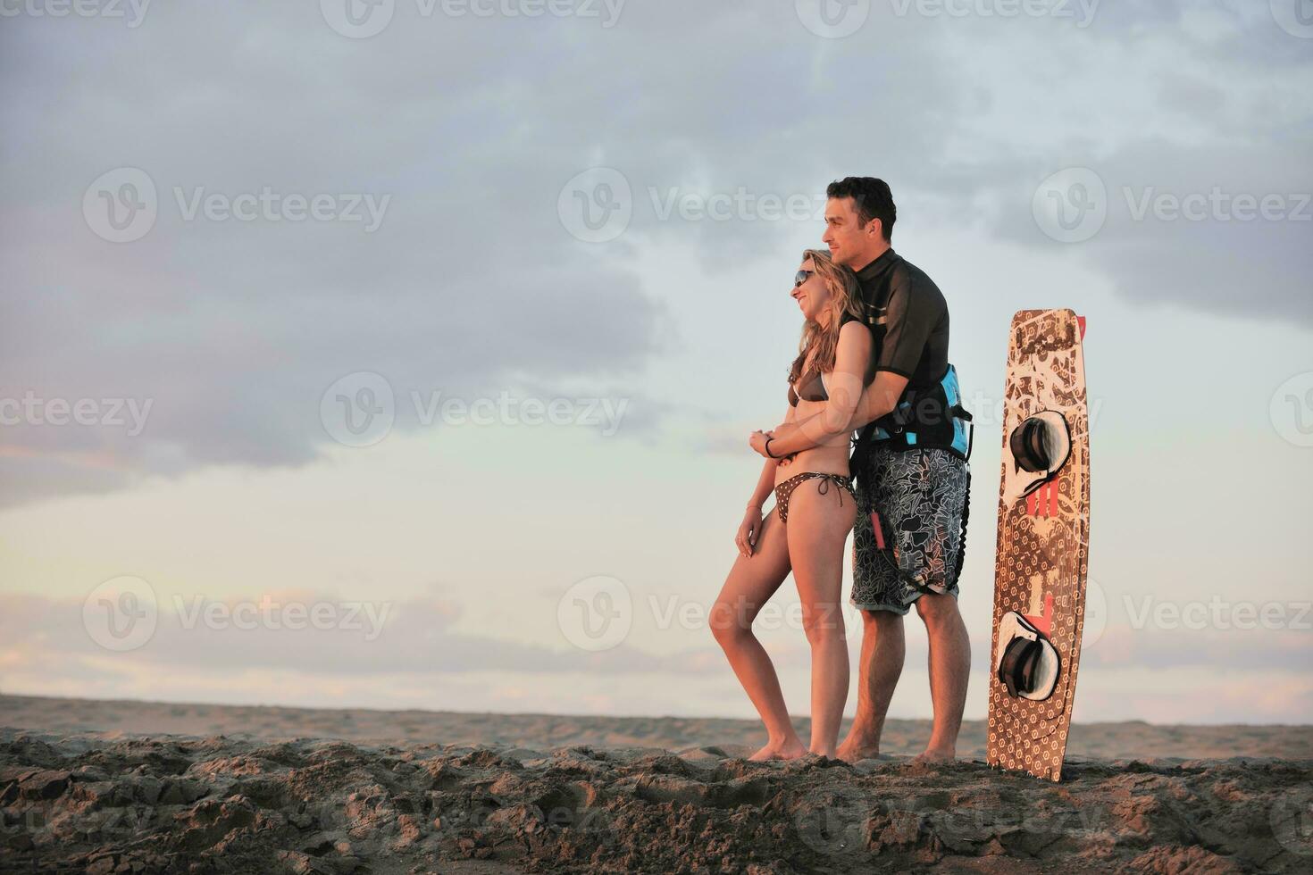surf couple posing at beach on sunset photo