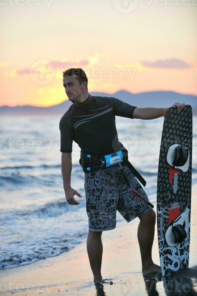 Portrait of a young  kitsurf  man at beach on sunset photo