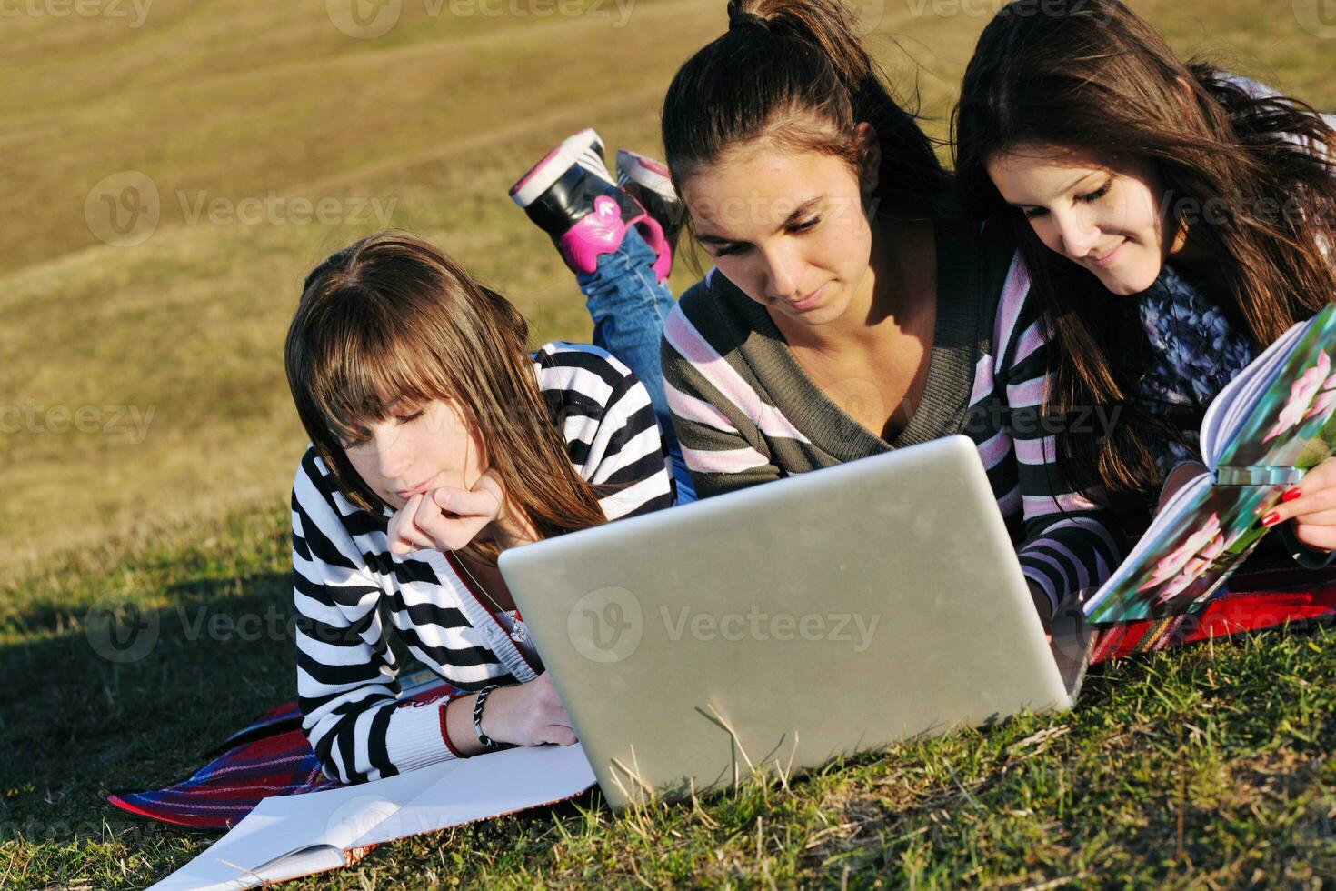 grupo de adolescentes trabajando en una laptop al aire libre foto