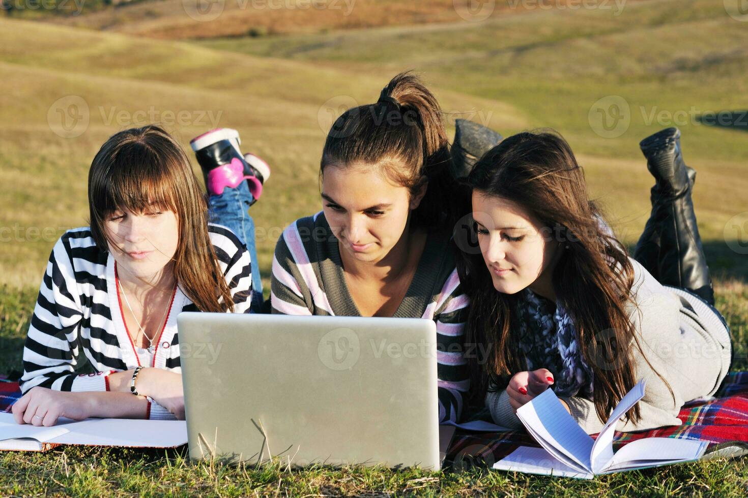 grupo de adolescentes trabajando en una laptop al aire libre foto