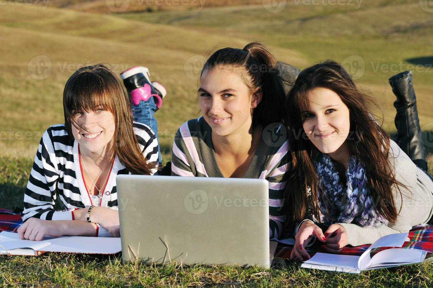 grupo de adolescentes trabajando en una laptop al aire libre foto