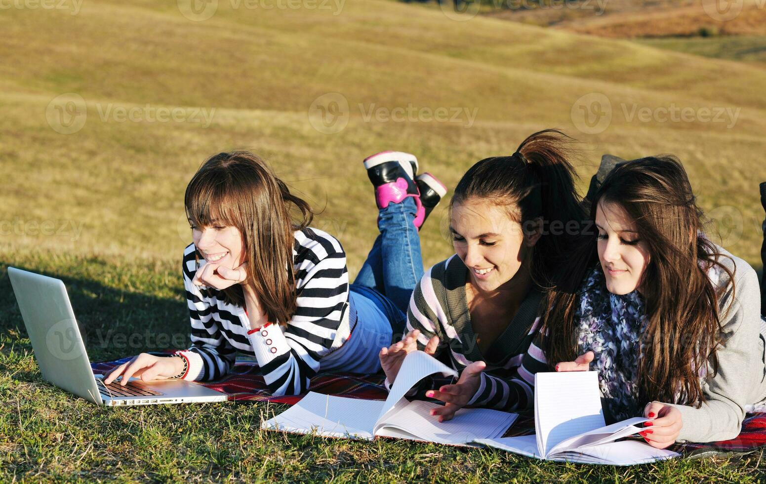 group of teens working on laptop outdoor photo