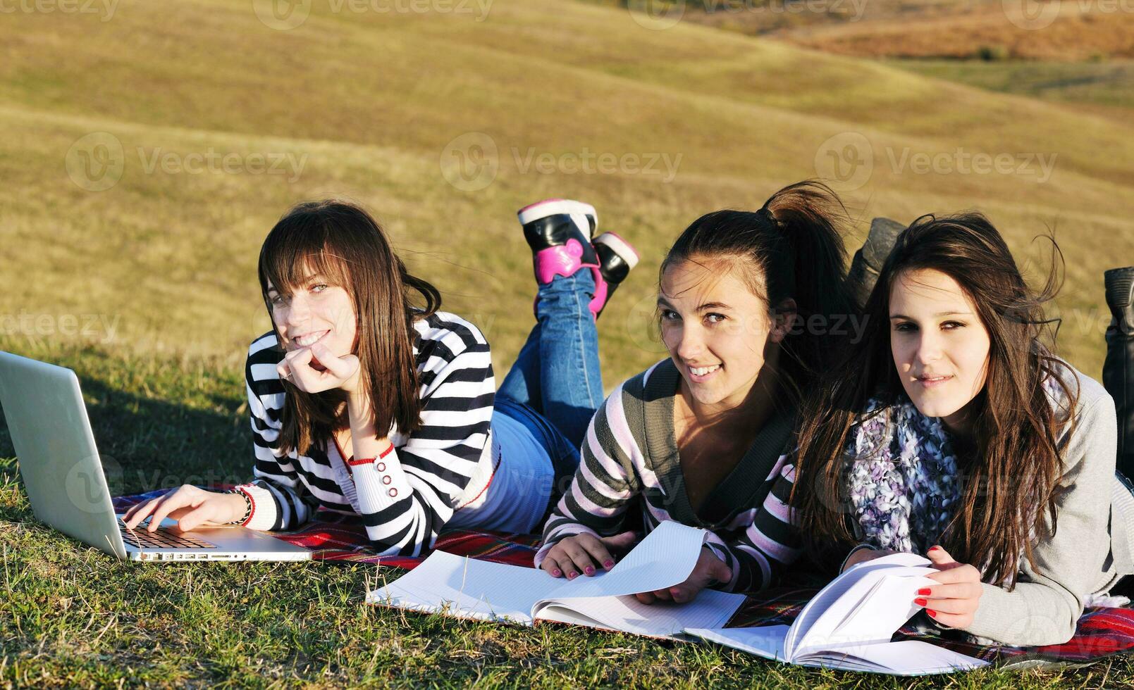 group of teens working on laptop outdoor photo