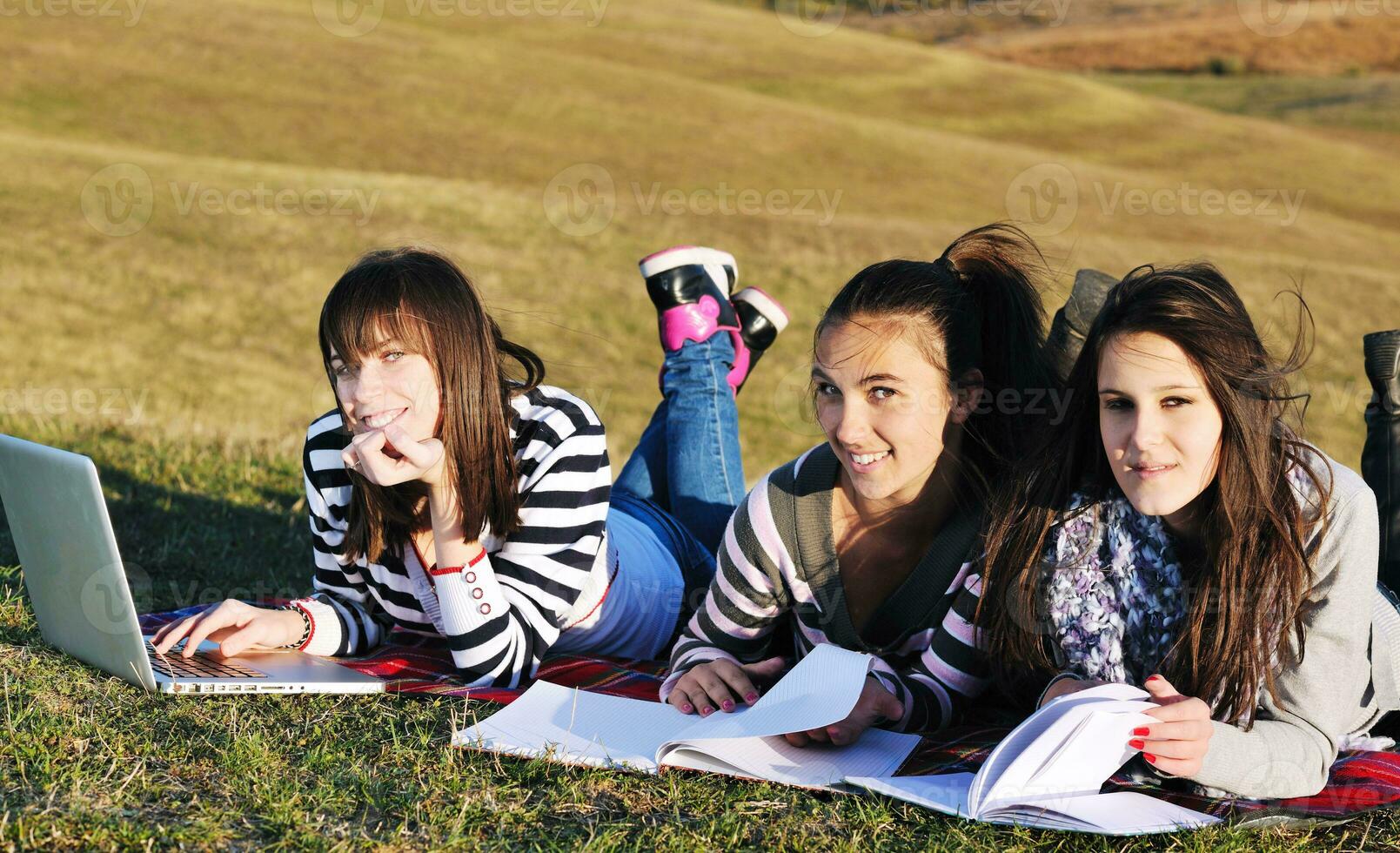 grupo de adolescentes trabajando en una laptop al aire libre foto