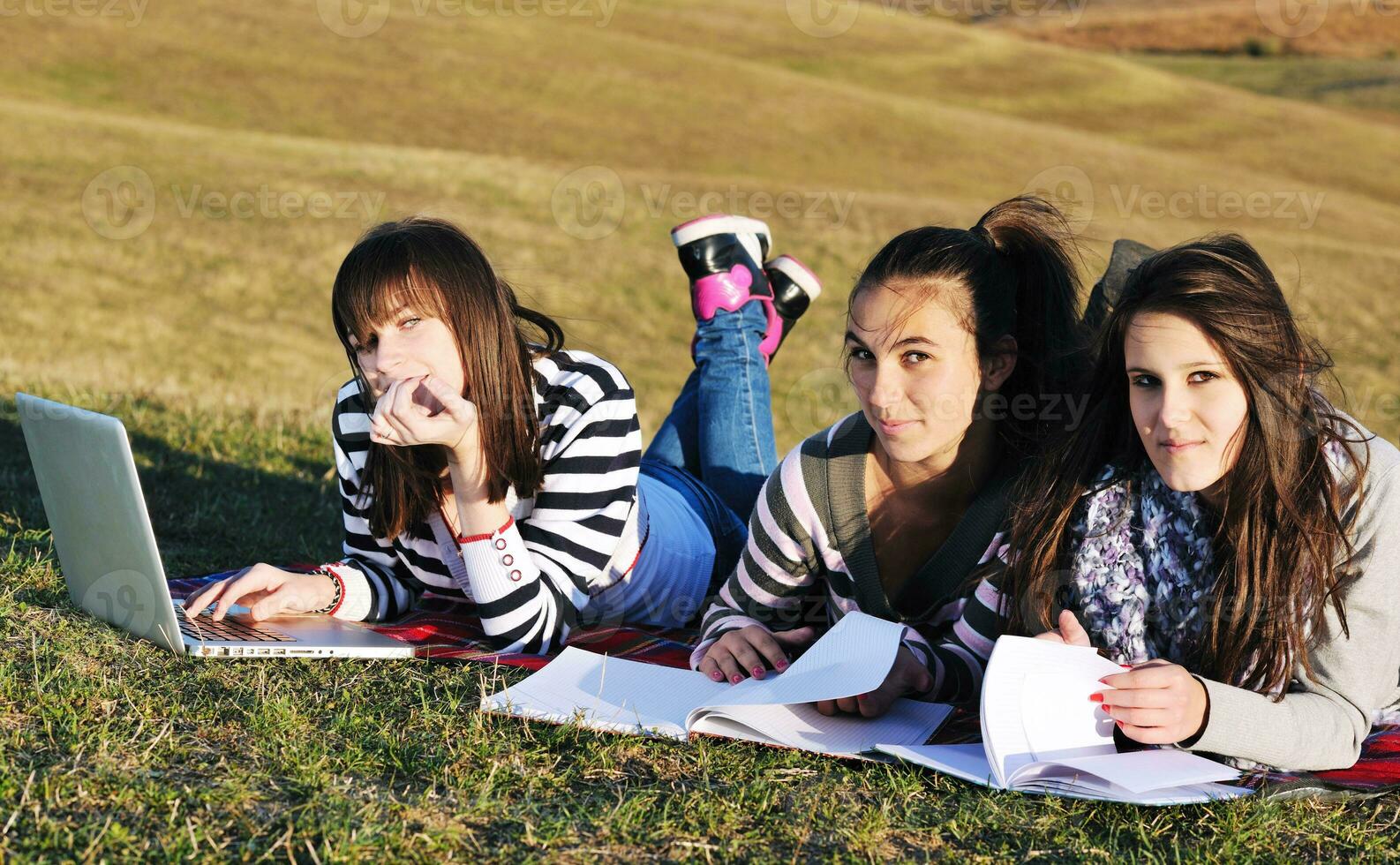 group of teens working on laptop outdoor photo