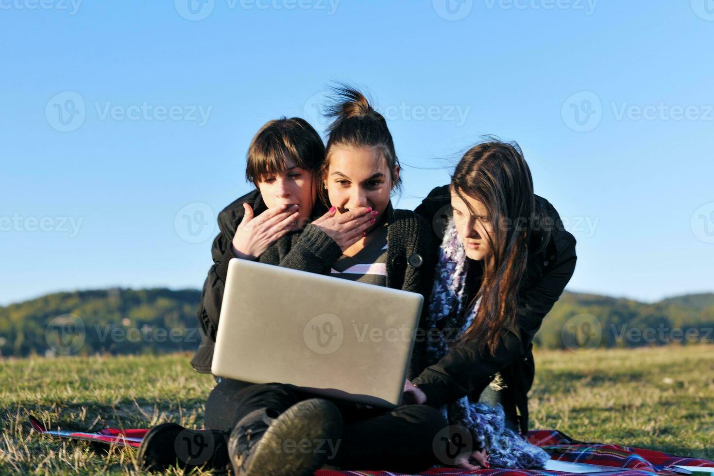 group of teens working on laptop outdoor photo