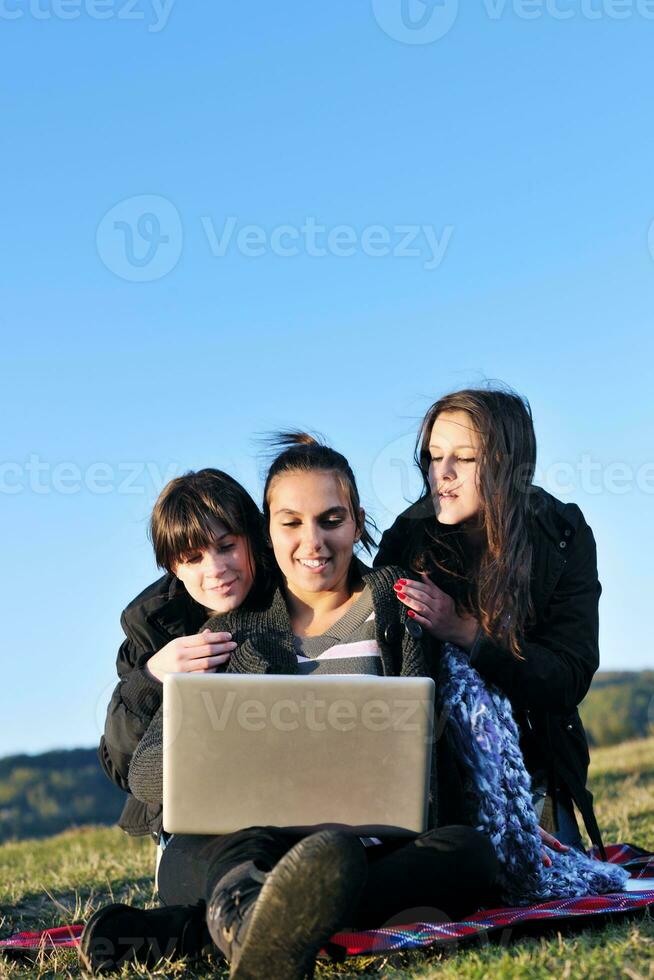 grupo de adolescentes trabajando en una laptop al aire libre foto