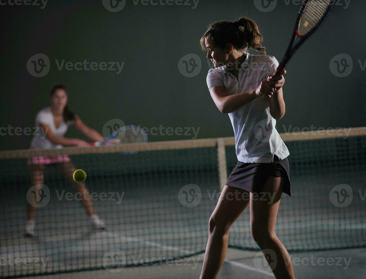 young girls playing tennis game indoor photo