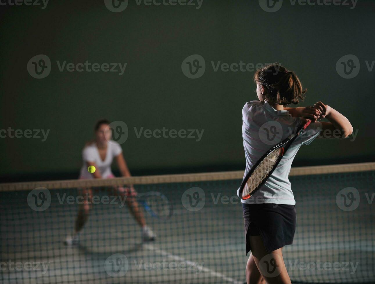 young girls playing tennis game indoor photo