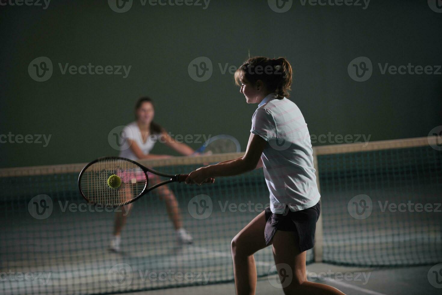 young girls playing tennis game indoor photo