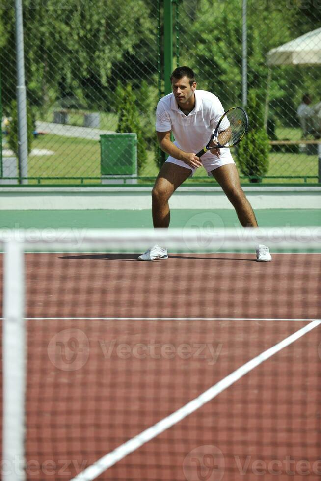 joven hombre jugar tenis al aire librejoven hombre jugar tenis al aire libre foto