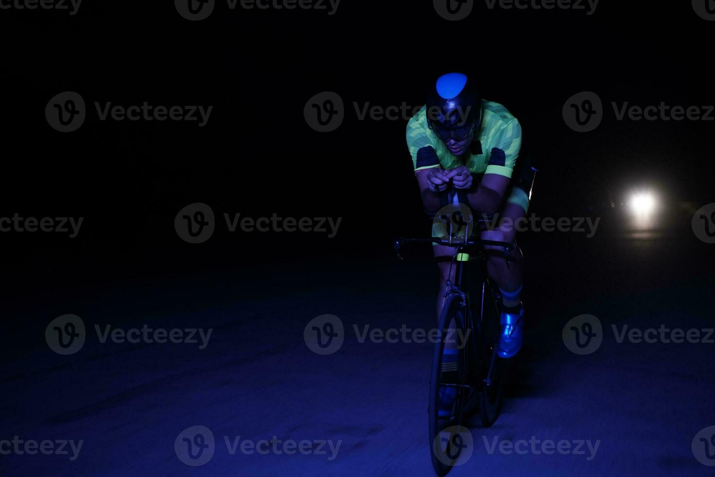 atleta de triatlón montando bicicleta rápido por la noche foto