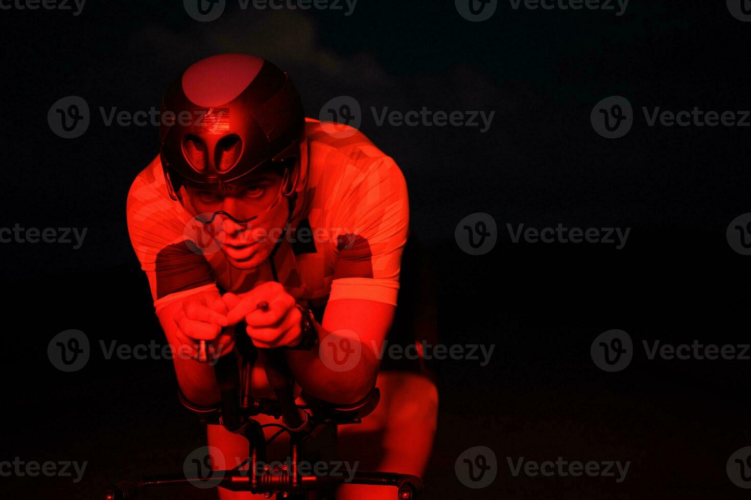 triathlon athlete riding bike fast at night photo