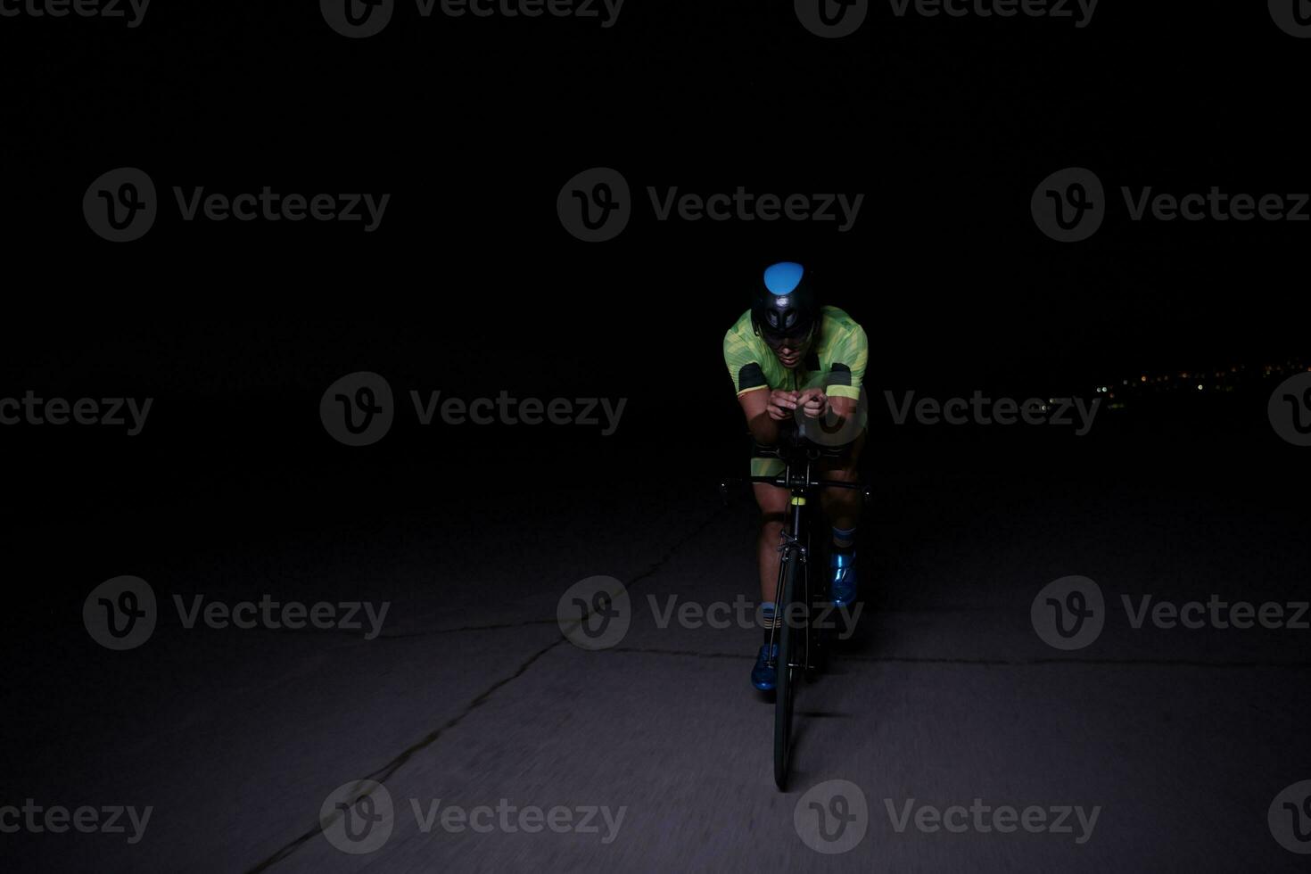 triathlon athlete riding bike fast  at night photo