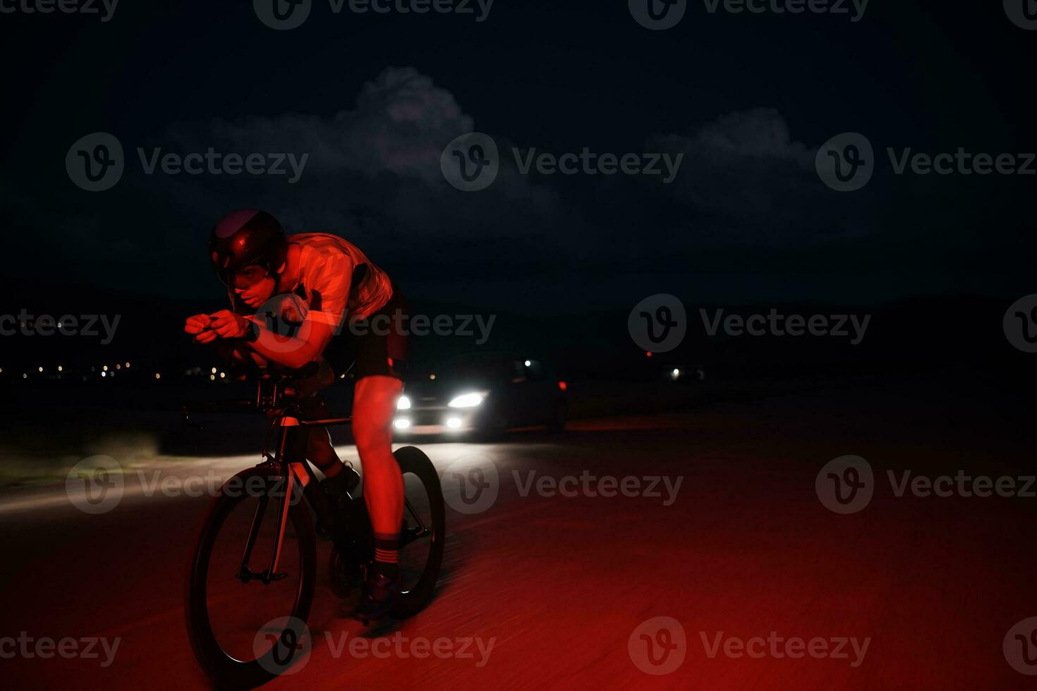 atleta de triatlón montando bicicleta rápido por la noche foto