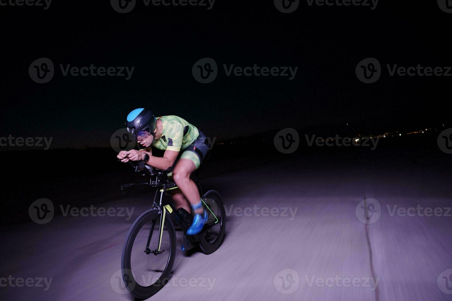 triathlon athlete riding bike fast  at night photo