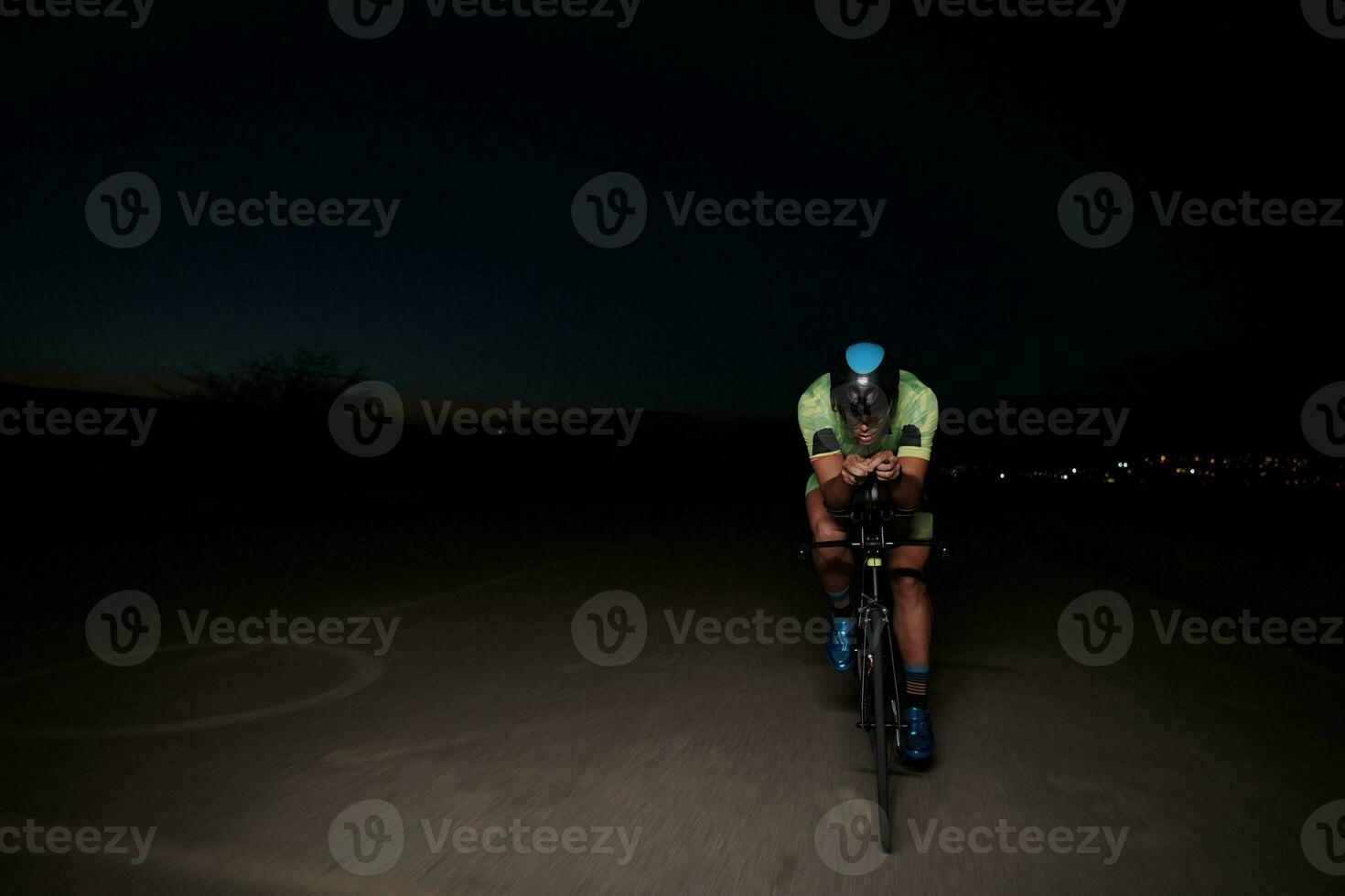 atleta de triatlón montando bicicleta rápido por la noche foto