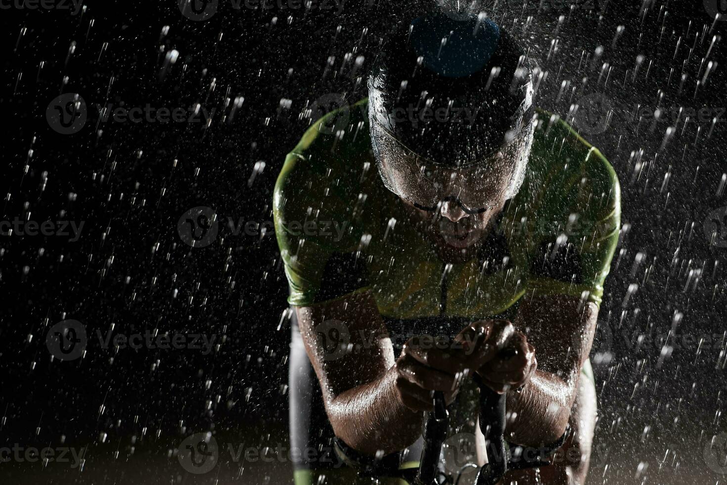 triathlon athlete riding bike  fast on rainy night photo