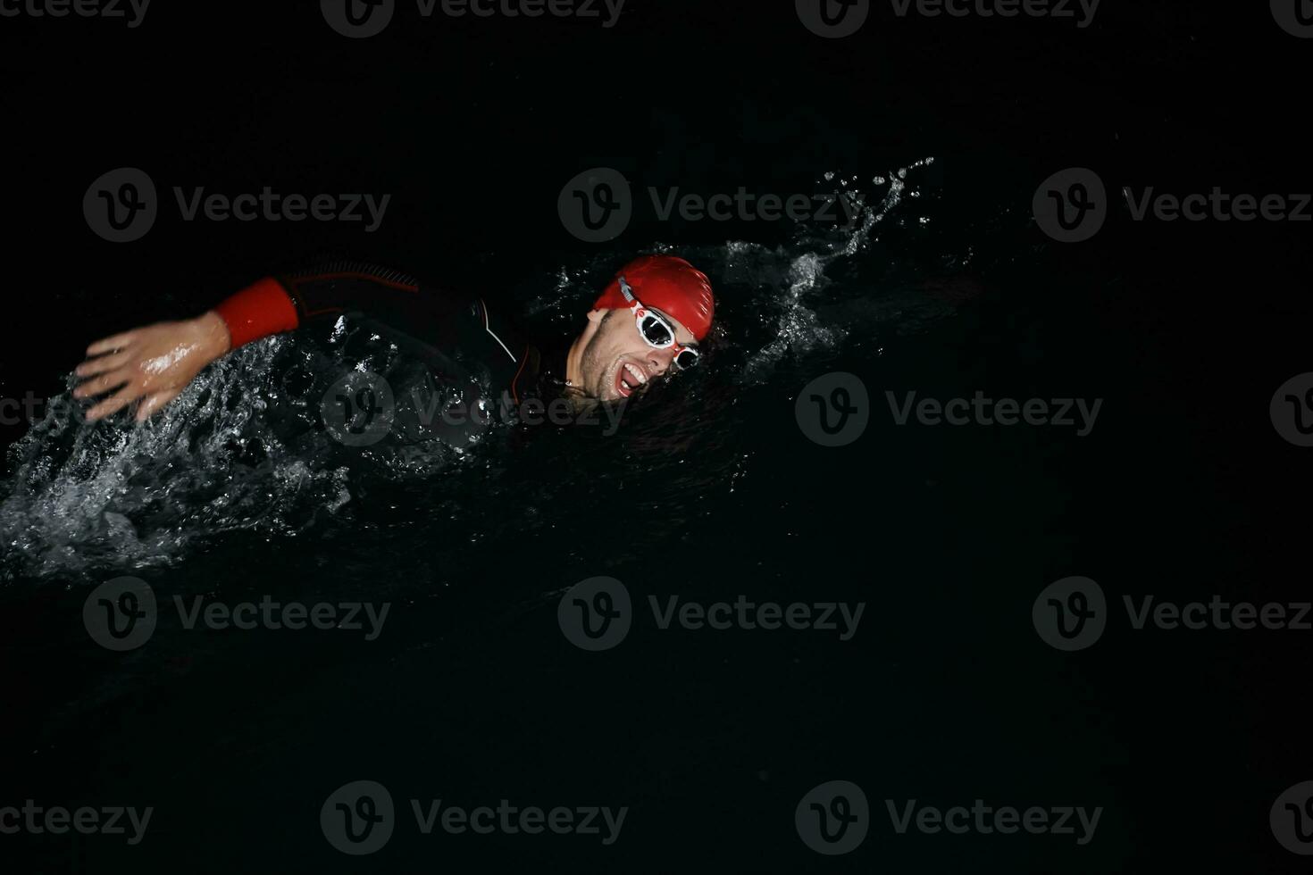 triathlon athlete swimming in dark night  wearing wetsuit photo