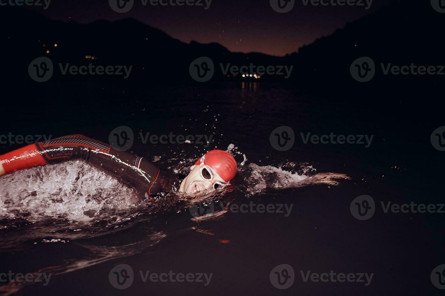 triathlon athlete swimming in dark night  wearing wetsuit photo