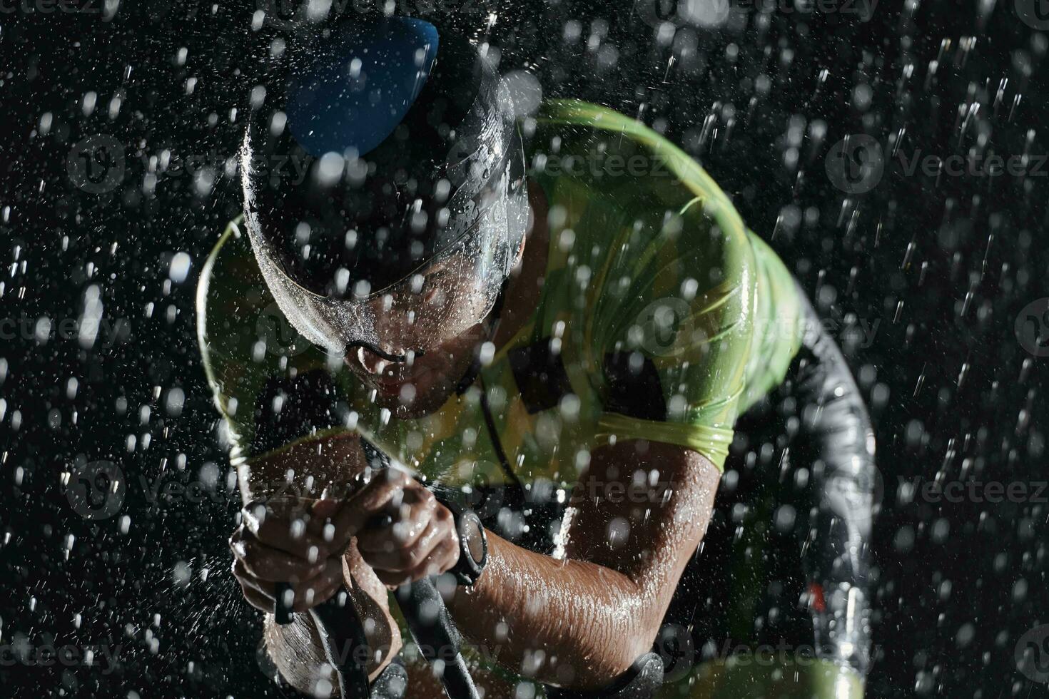 triathlon athlete riding bike  fast on rainy night photo