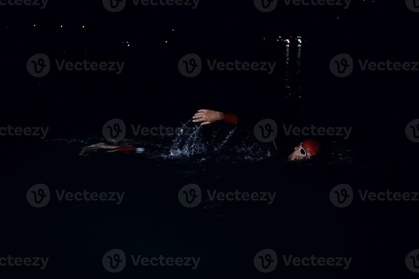 triathlon athlete swimming in dark night  wearing wetsuit photo