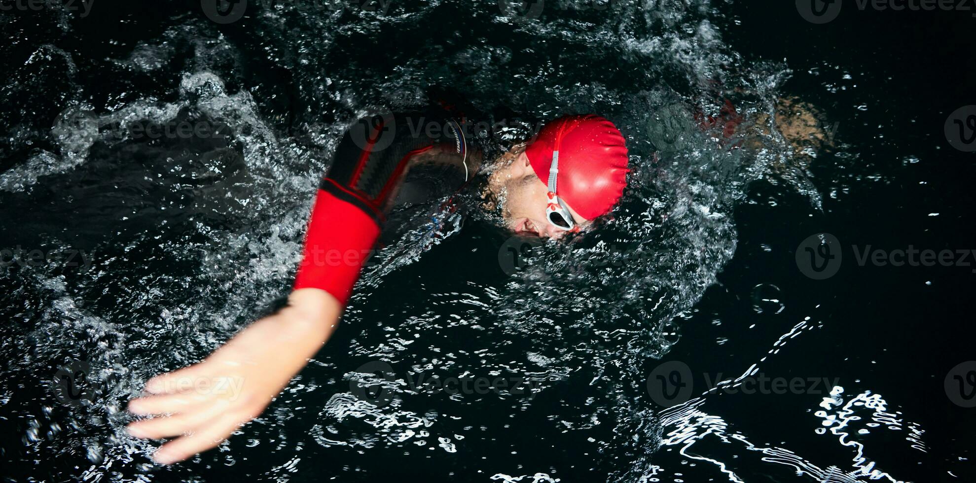 atleta de triatlón nadando en la noche oscura con traje de neopreno foto