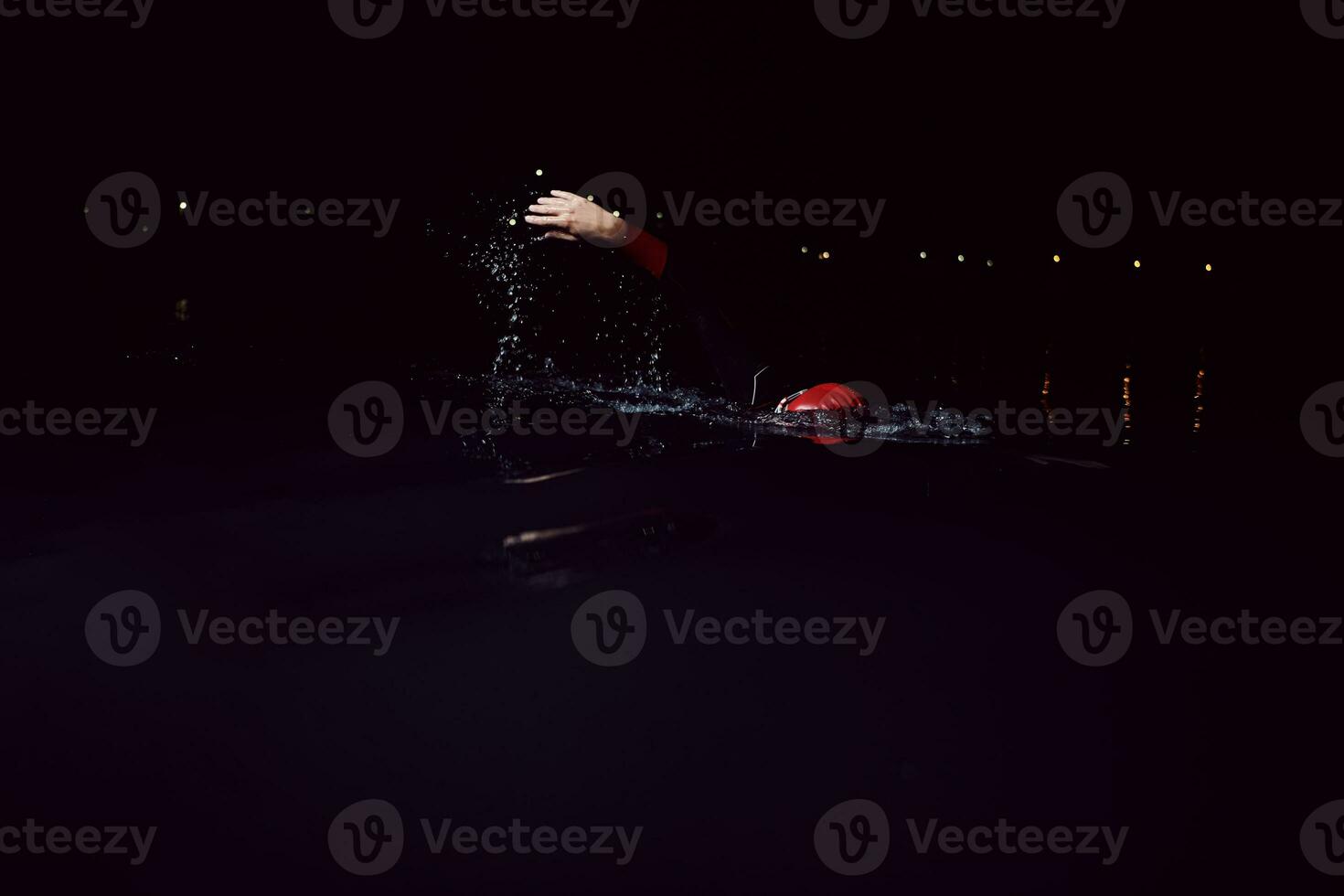 triathlon athlete swimming in dark night  wearing wetsuit photo