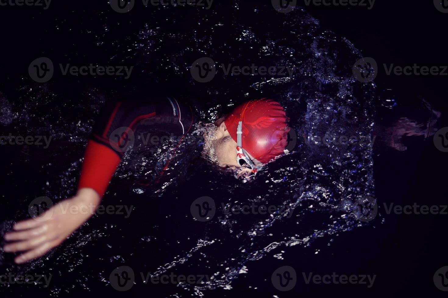 triathlon athlete swimming in dark night  wearing wetsuit photo