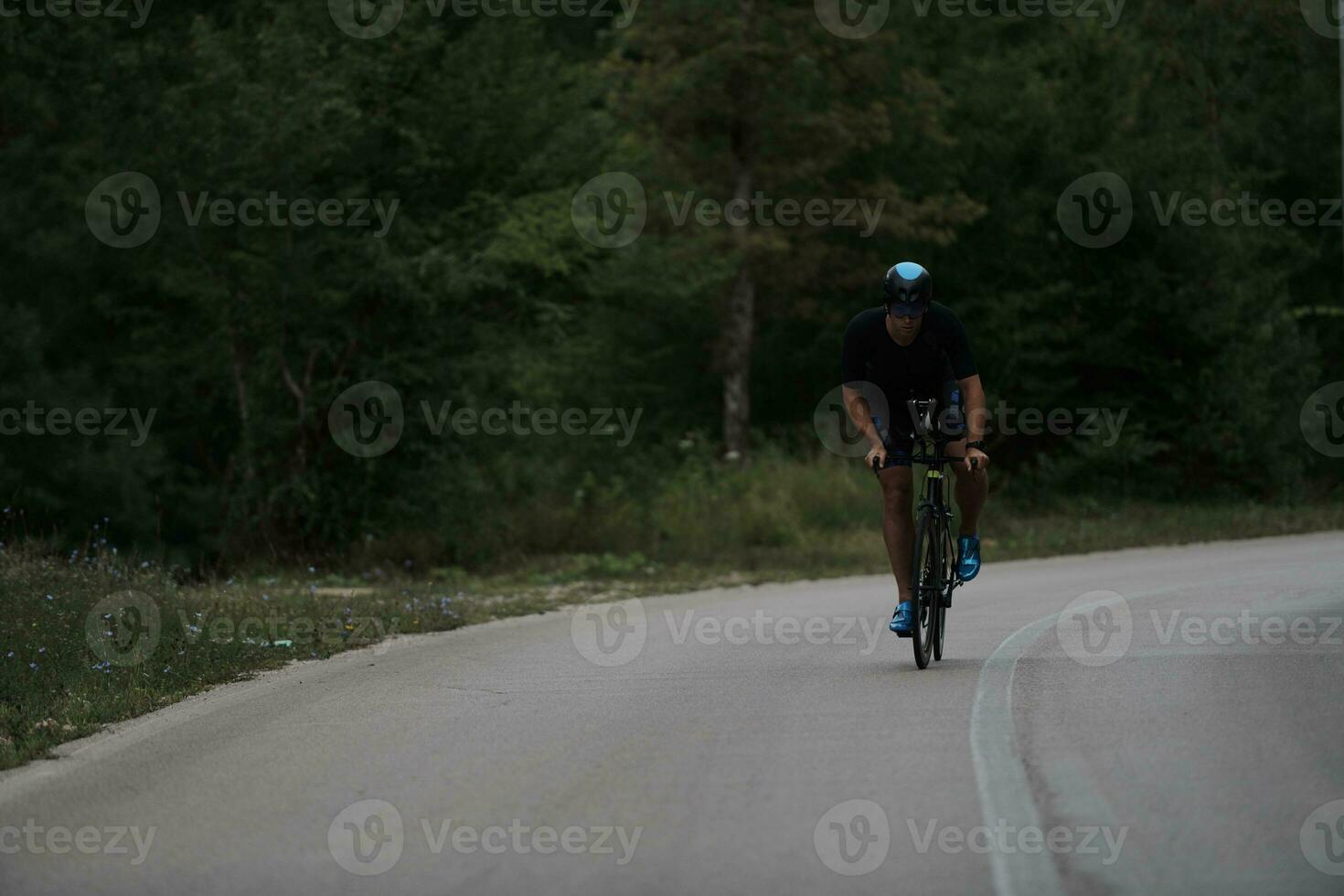 atleta de triatlón montando una bicicleta vestida de negro foto