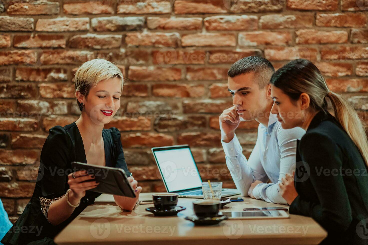 Happy businesspeople smiling cheerfully during a meeting in a coffee shop. Group of successful business professionals working as a team in a multicultural workplace. photo