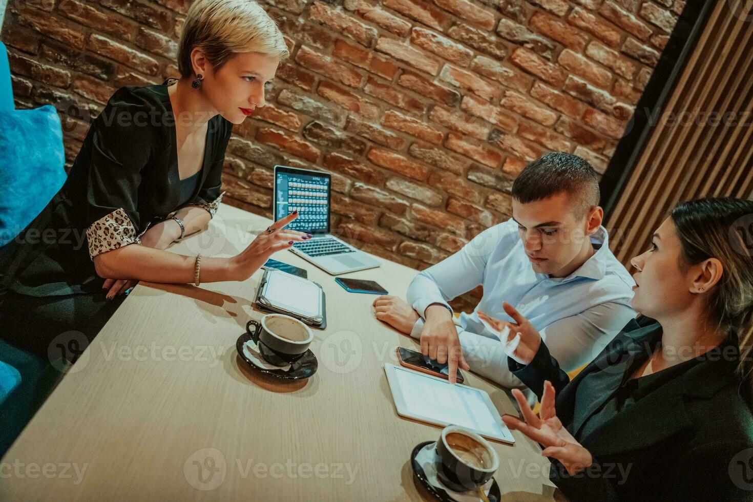 Happy businesspeople smiling cheerfully during a meeting in a coffee shop. Group of successful business professionals working as a team in a multicultural workplace. photo