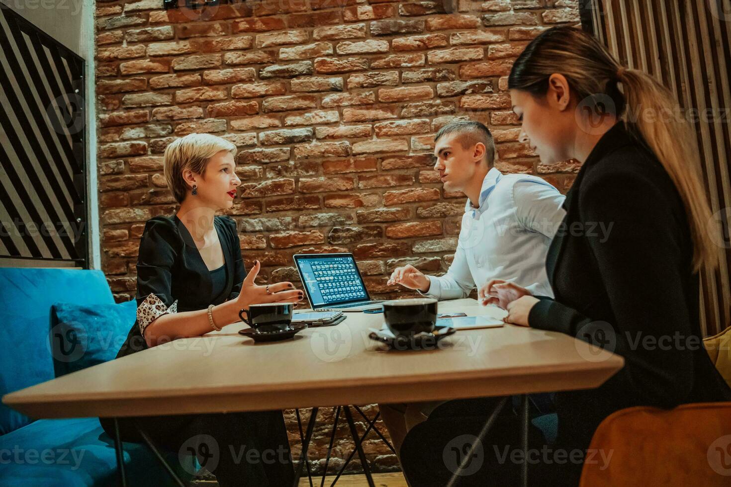 Happy businesspeople smiling cheerfully during a meeting in a coffee shop. Group of successful business professionals working as a team in a multicultural workplace. photo
