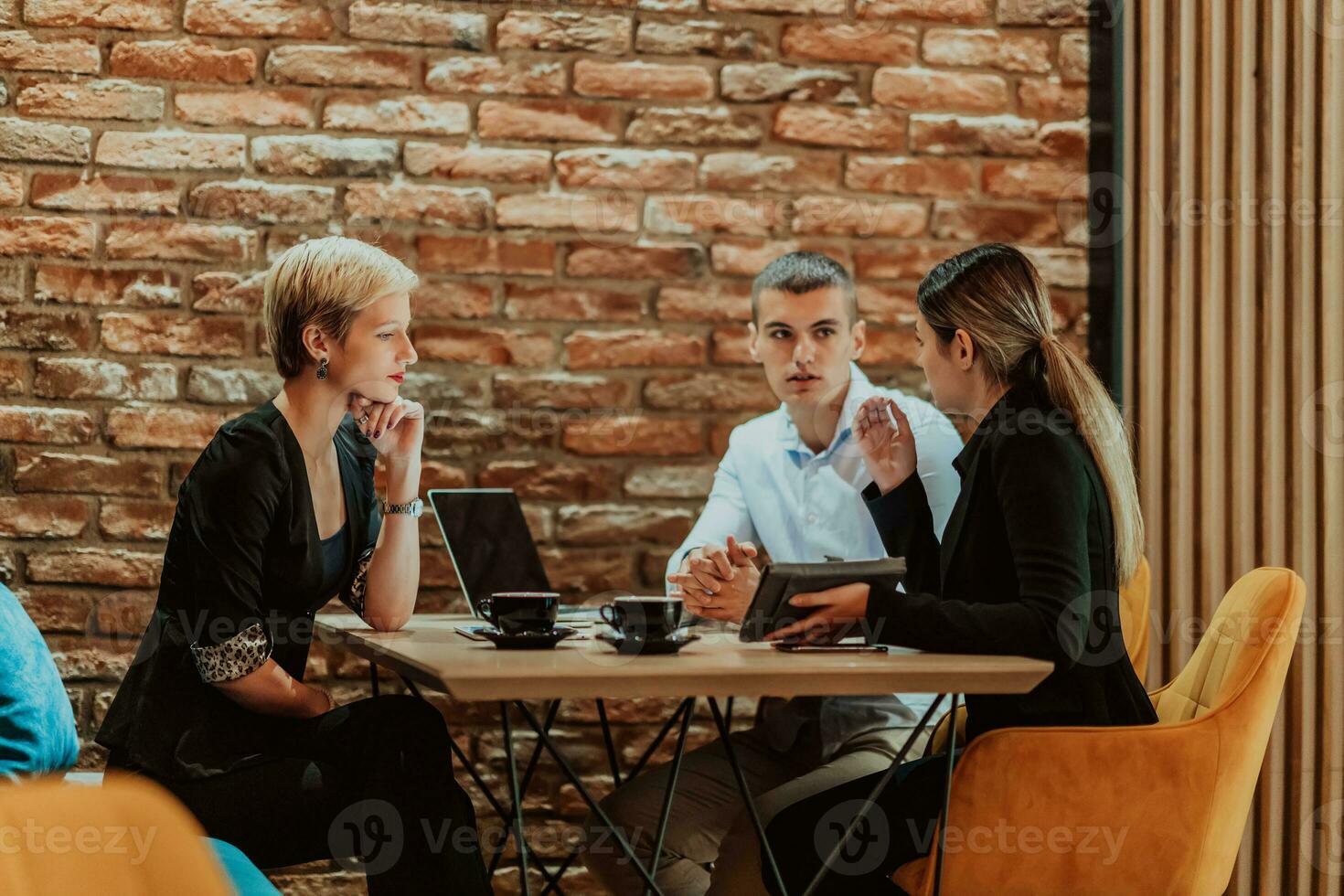 Happy businesspeople smiling cheerfully during a meeting in a coffee shop. Group of successful business professionals working as a team in a multicultural workplace. photo