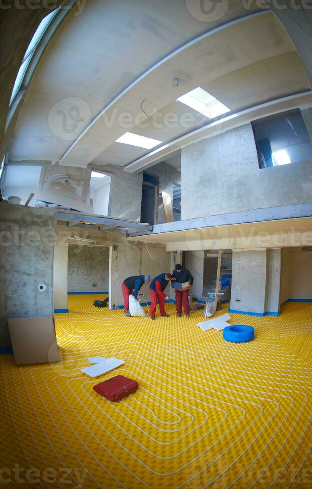workers installing underfloor heating system photo
