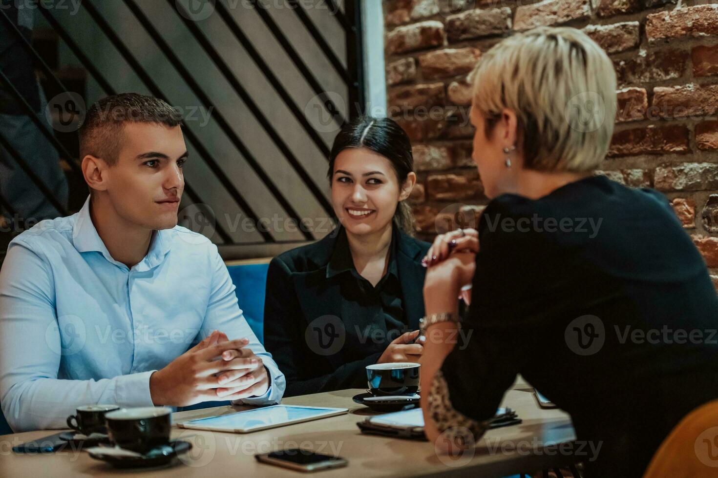 Happy businesspeople smiling cheerfully during a meeting in a coffee shop. Group of successful business professionals working as a team in a multicultural workplace. photo