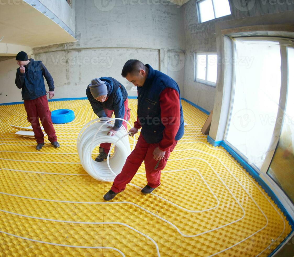 workers installing underfloor heating system photo