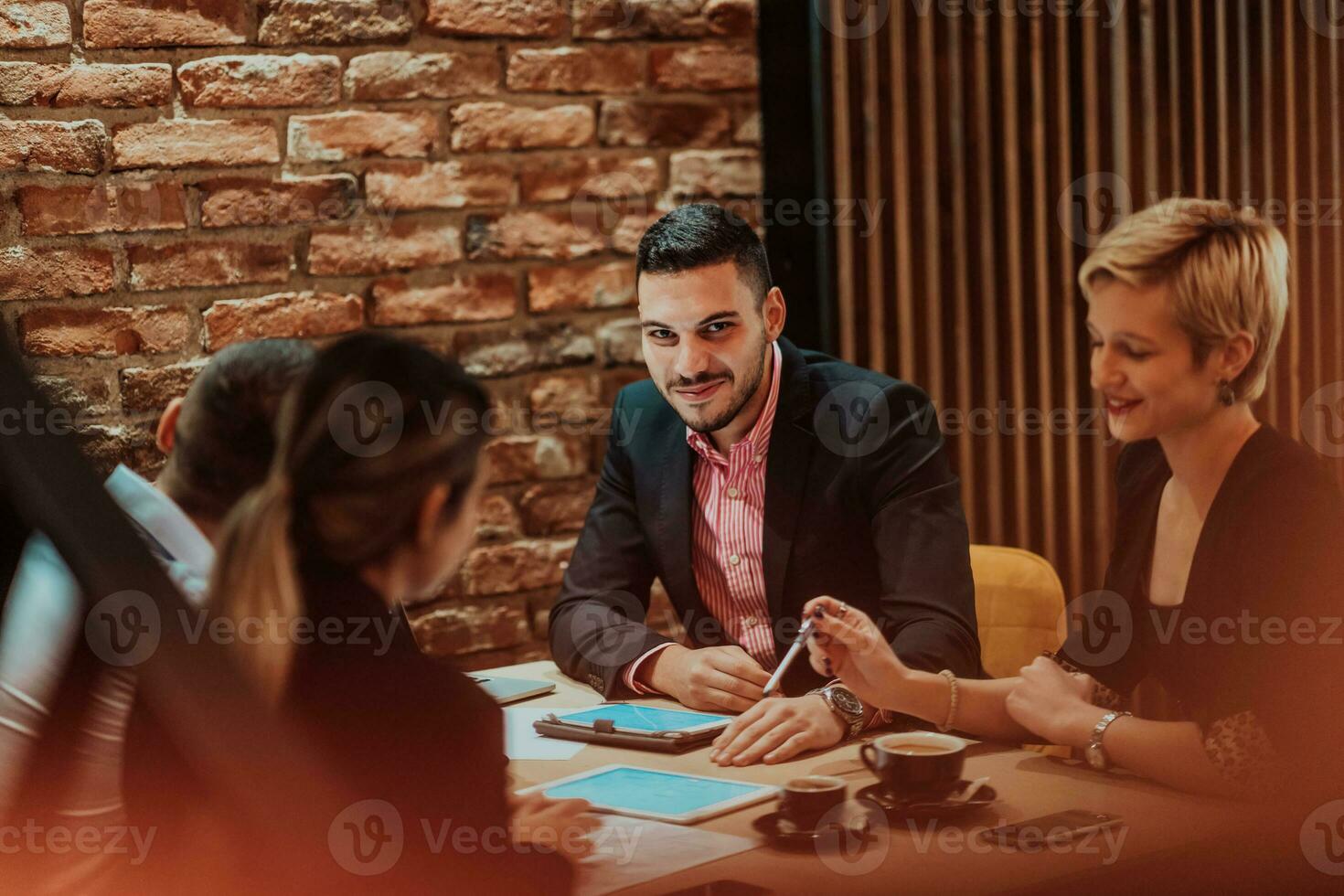 Happy businesspeople smiling cheerfully during a meeting in a coffee shop. Group of successful business professionals working as a team in a multicultural workplace. photo