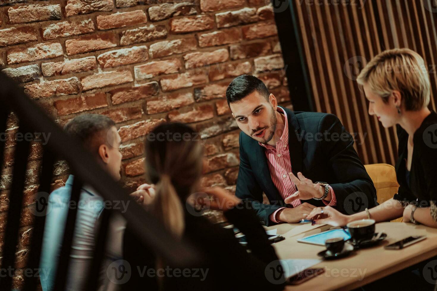 Happy businesspeople smiling cheerfully during a meeting in a coffee shop. Group of successful business professionals working as a team in a multicultural workplace. photo
