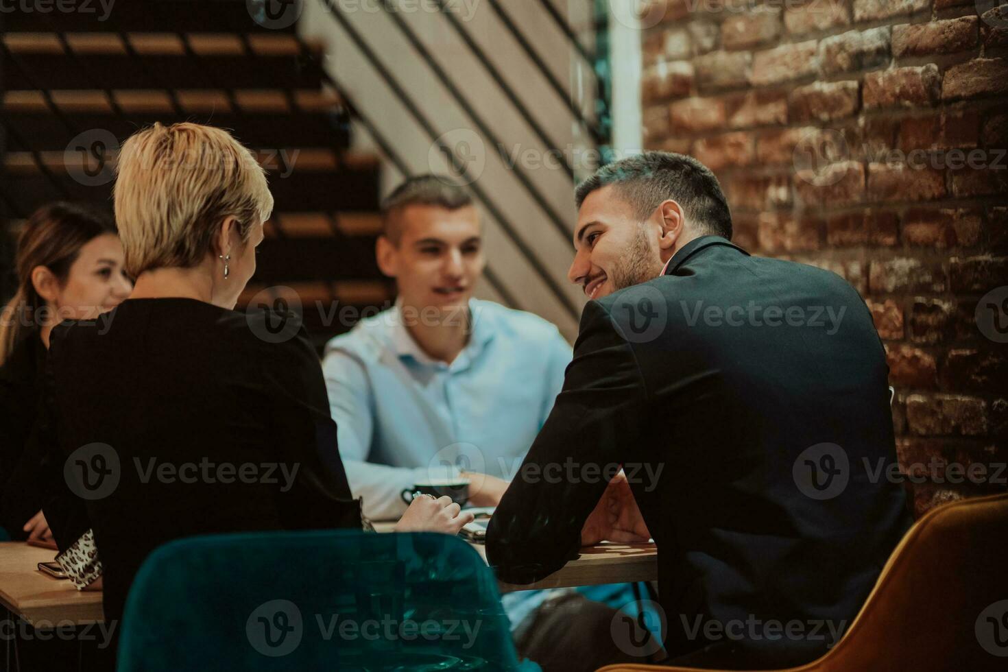 Happy businesspeople smiling cheerfully during a meeting in a coffee shop. Group of successful business professionals working as a team in a multicultural workplace. photo