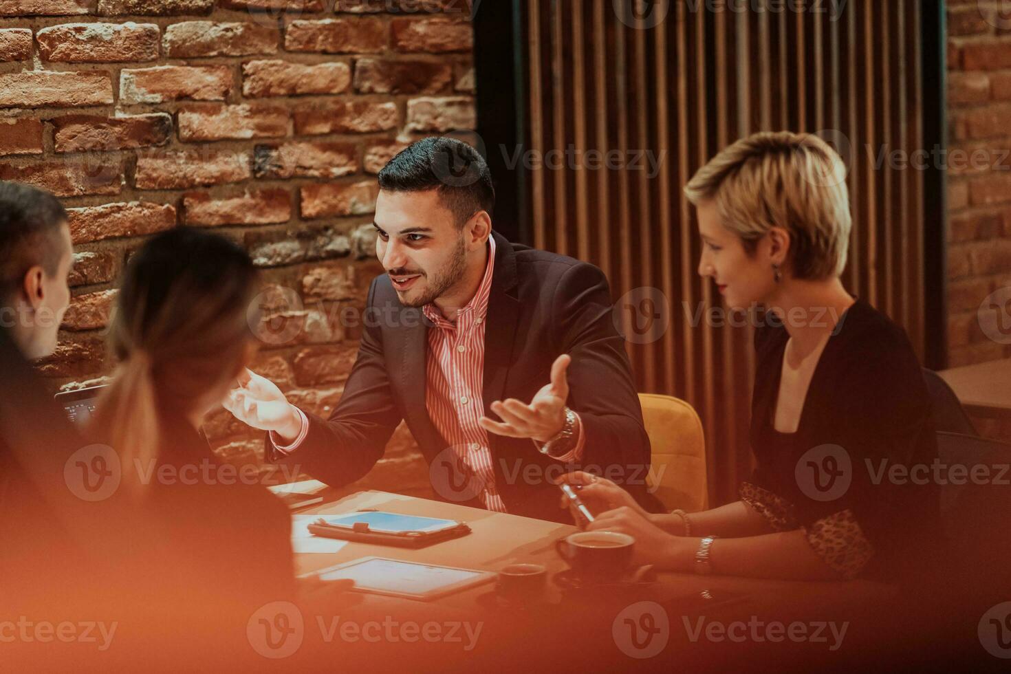 Happy businesspeople smiling cheerfully during a meeting in a coffee shop. Group of successful business professionals working as a team in a multicultural workplace. photo