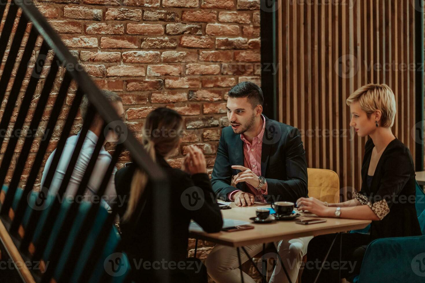 Happy businesspeople smiling cheerfully during a meeting in a coffee shop. Group of successful business professionals working as a team in a multicultural workplace. photo
