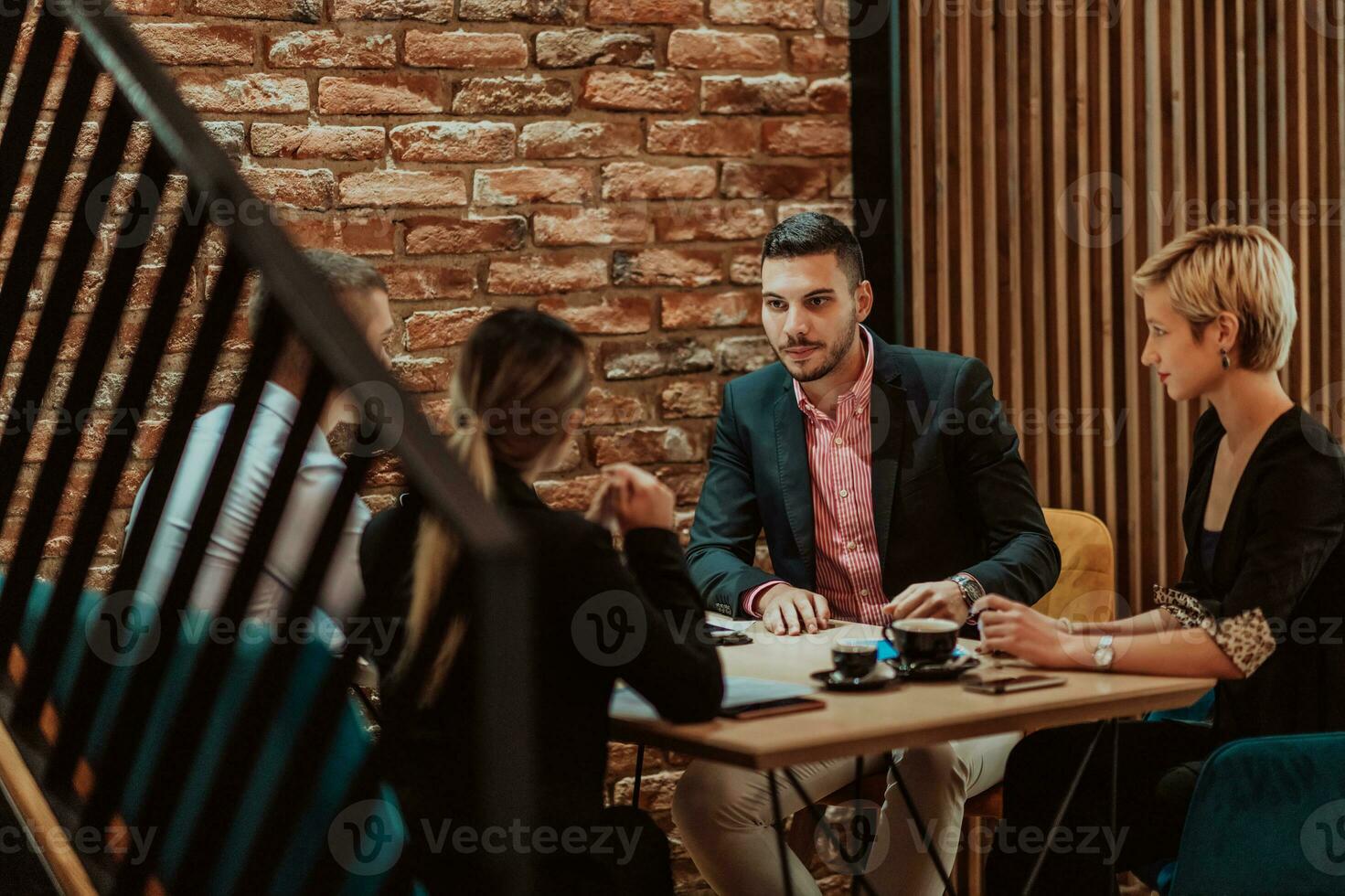 Happy businesspeople smiling cheerfully during a meeting in a coffee shop. Group of successful business professionals working as a team in a multicultural workplace. photo