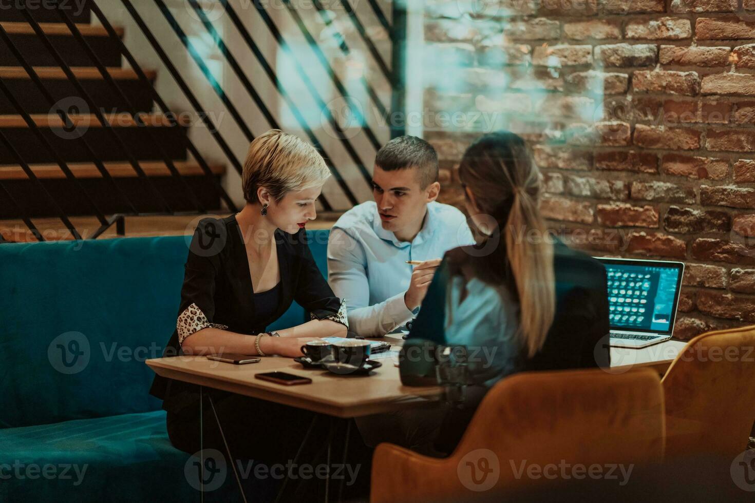 Happy businesspeople smiling cheerfully during a meeting in a coffee shop. Group of successful business professionals working as a team in a multicultural workplace. photo