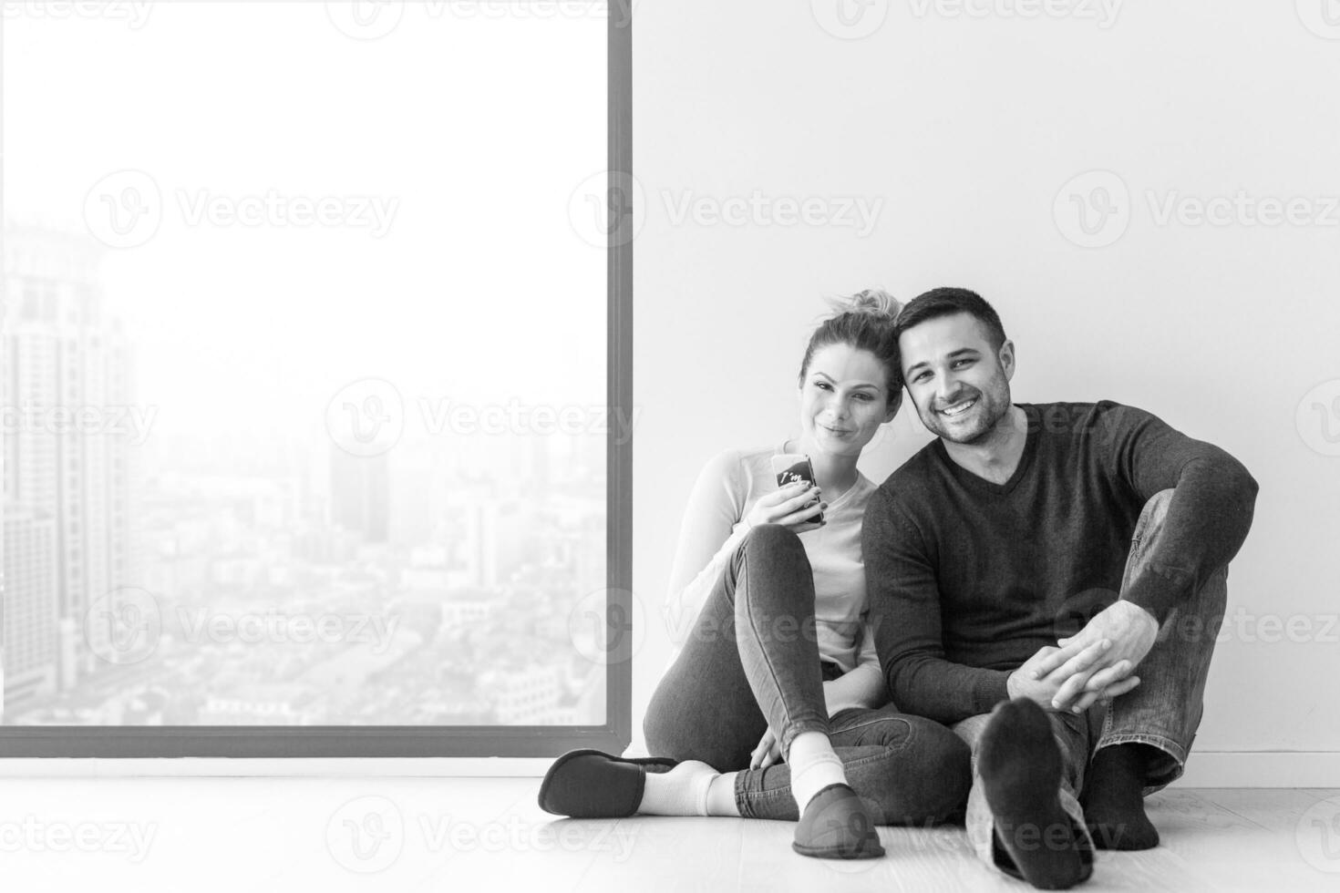 young couple sitting on the floor near window at home photo