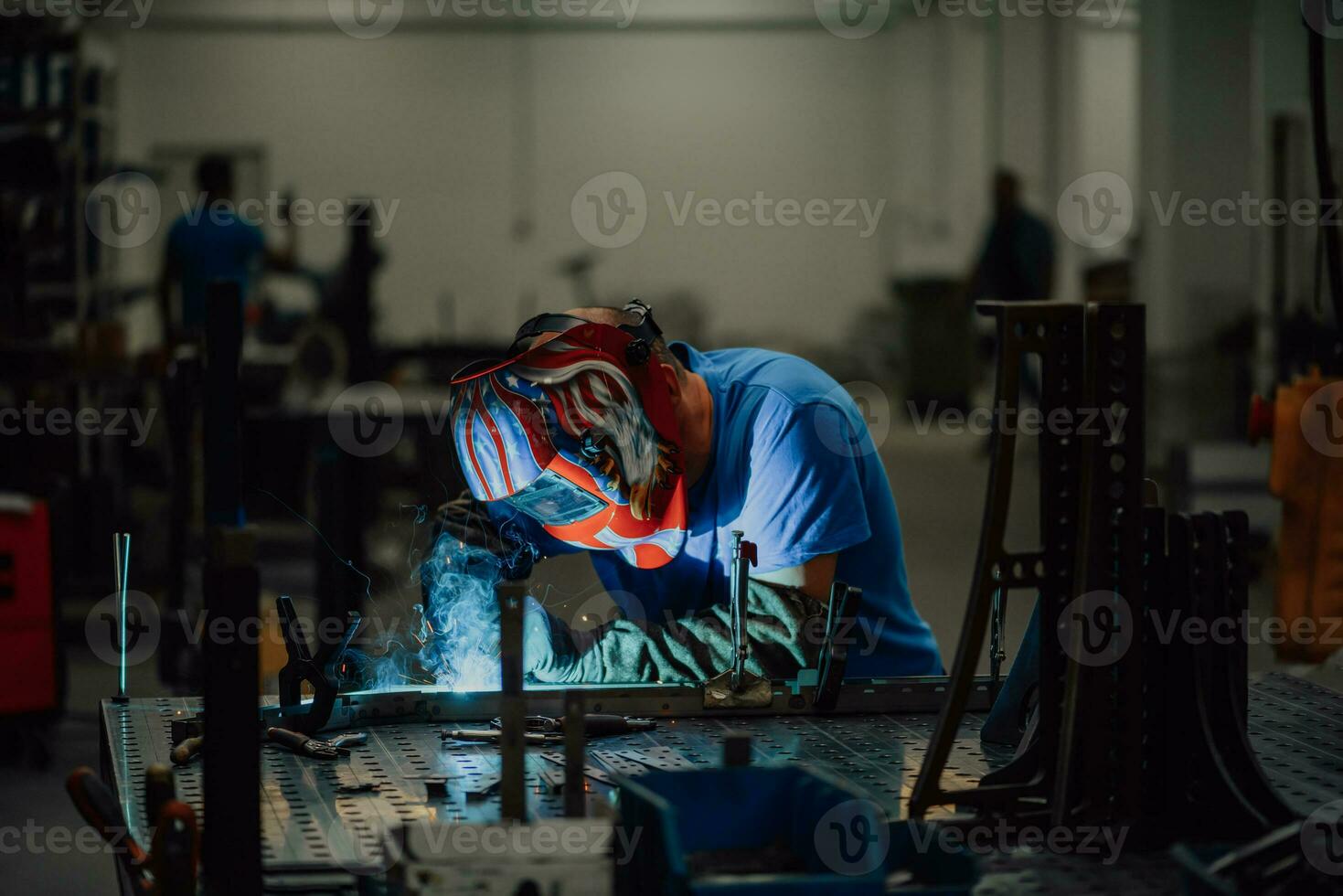 soldador profesional de la industria pesada que trabaja dentro de la fábrica, usa casco y comienza a soldar. enfoque selectivo foto